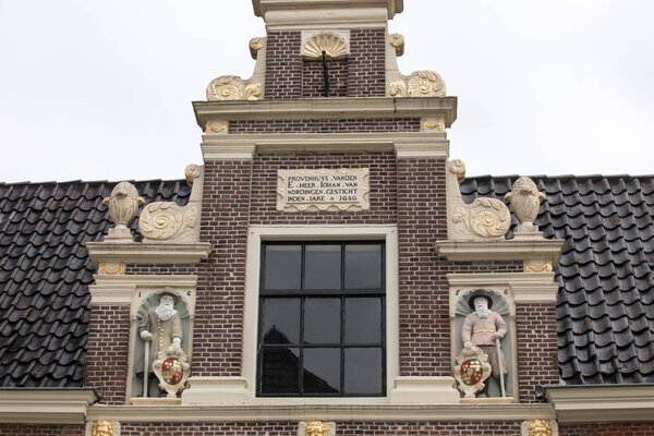 Top gable with memorial stone and sculptures of Huis van Achten in Alkmaar, Netherlands 