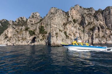 Gemilerde teknedeki turist ve Uçurumun kıyısında ve Capri Adası ile görüntüleyin. İtalya