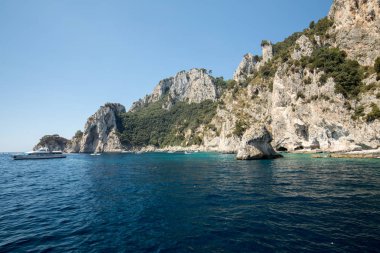 Gemilerde teknedeki turist ve Uçurumun kıyısında ve Capri Adası ile görüntüleyin. İtalya
