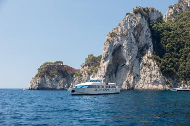  Gemilerde teknedeki turist ve Uçurumun kıyısında ve Capri Adası ile görüntüleyin. İtalya