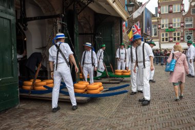 Alkmaar, Hollanda - 21 Nisan 2017: Alkmaar, Hollanda ünlü Hollandalı peynir pazarında birçok peynir ile yürüyüş uçak gemisi. Waagplein Meydanı'nda olay olur. 