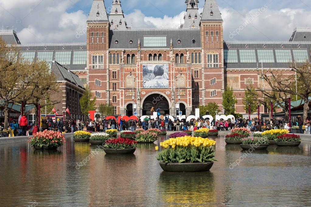 AMSTERDAM, NETHERLANDS - APRIL 22 2017: Rijksmuseum National Museum with I Amsterdam sign and tulips in the reflecting pool. Amsterdam, Netherlands