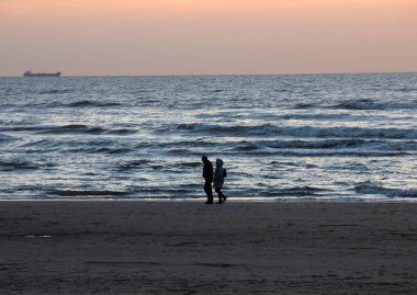 Erkek ve kadın gün batımında sahilde yürüyüş.