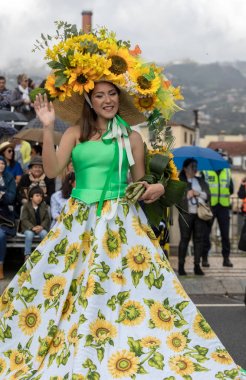 Funchal; Madeira; Portekiz - 22 Nisan; 2018: ayçiçeği motifli renkli elbiseli kadın dans Madeira çiçek Festivali geçit töreninde Funchal, Madeira Adası üzerinde. Portuga