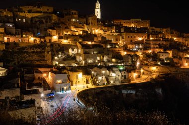 Matera 'daki antik Sassi bölgesinde geceleri, antik mağara evleri ile tanınan şaşırtıcı aydınlık binalar. Basilicata. İtalya
