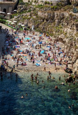 Polignano a Mare, İtalya - 17 Eylül 2019: İnsanlar Polignano a Mare, Adriyatik Denizi, Apulia, Bari ili, İtalya 'daki sevimli Lama Monachile plajında dinleniyor ve yüzüyorlar,