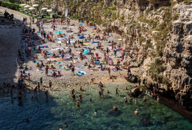 Polignano a Mare, İtalya - 17 Eylül 2019: İnsanlar Polignano a Mare, Adriyatik Denizi, Apulia, Bari ili, İtalya 'daki sevimli Lama Monachile plajında dinleniyor ve yüzüyorlar,