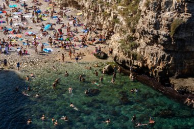 Polignano a Mare, İtalya - 17 Eylül 2019: İnsanlar Polignano a Mare, Adriyatik Denizi, Apulia, Bari ili, İtalya 'daki sevimli Lama Monachile plajında dinleniyor ve yüzüyorlar,