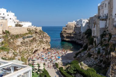 Polignano, İtalya - 17 Eylül 2019: İnsanlar Polignano a Mare, Adriyatik Denizi, Apulia, Bari ili, İtalya 'daki sevimli Lama Monachile plajında dinleniyor ve yüzüyorlar,