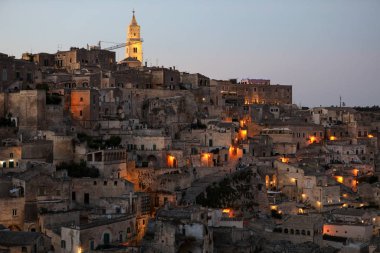 Matera 'daki antik Sassi bölgesinde geceleri, antik mağara evleri ile tanınan şaşırtıcı aydınlık binalar. Basilicata. İtalya