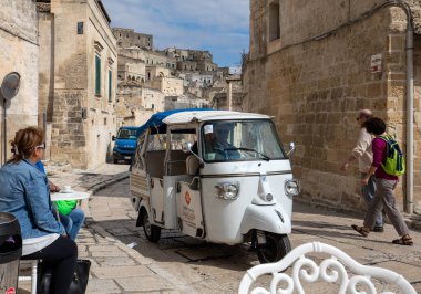 Matera, İtalya - 20 Eylül 2019: Matera şehrinde tarihi bir bölge olan Sassi di Matera 'da bir turist taksisi olarak kullanılan Piaggio Ape Calessino, antik mağara evleri ile tanınır. Basilicata. İtalya