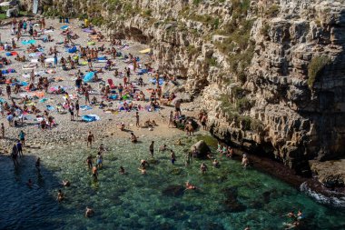 Polignano a Mare, İtalya - 17 Eylül 2019: İnsanlar Polignano a Mare, Adriyatik Denizi, Apulia, Bari ili, İtalya 'daki sevimli Lama Monachile plajında dinleniyor ve yüzüyorlar,
