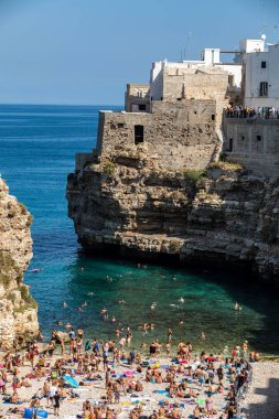 Polignano, İtalya - 17 Eylül 2019: İnsanlar Polignano a Mare, Adriyatik Denizi, Apulia, Bari ili, İtalya 'daki sevimli Lama Monachile plajında dinleniyor ve yüzüyorlar,