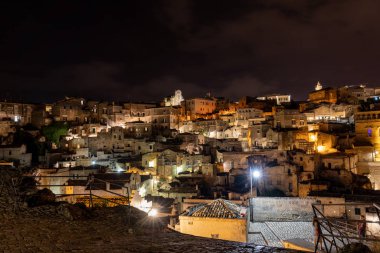Matera 'daki antik Sassi bölgesinde geceleri, antik mağara evleri ile tanınan şaşırtıcı aydınlık binalar. Basilicata. İtalya