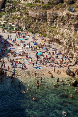 Polignano a Mare, İtalya - 17 Eylül 2019: İnsanlar Polignano a Mare, Adriyatik Denizi, Apulia, Bari ili, İtalya 'daki sevimli Lama Monachile plajında dinleniyor ve yüzüyorlar,