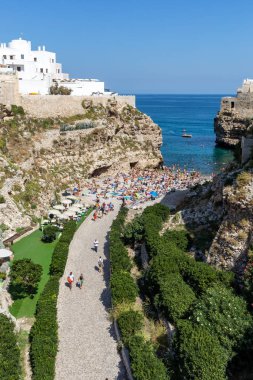 Polignano, İtalya - 17 Eylül 2019: İnsanlar Polignano a Mare, Adriyatik Denizi, Apulia, Bari ili, İtalya 'daki sevimli Lama Monachile plajında dinleniyor ve yüzüyorlar,