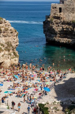 Polignano, İtalya - 17 Eylül 2019: İnsanlar Polignano a Mare, Adriyatik Denizi, Apulia, Bari ili, İtalya 'daki sevimli Lama Monachile plajında dinleniyor ve yüzüyorlar,