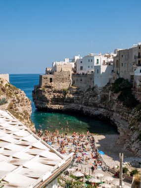 Polignano, İtalya - 17 Eylül 2019: İnsanlar Polignano a Mare, Adriyatik Denizi, Apulia, Bari ili, İtalya 'daki sevimli Lama Monachile plajında dinleniyor ve yüzüyorlar,