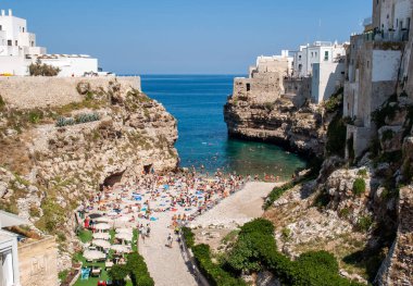 Polignano, İtalya - 17 Eylül 2019: İnsanlar Polignano a Mare, Adriyatik Denizi, Apulia, Bari ili, İtalya 'daki sevimli Lama Monachile plajında dinleniyor ve yüzüyorlar,