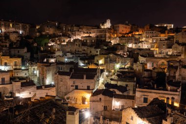 Matera 'daki antik Sassi bölgesinde geceleri, antik mağara evleri ile tanınan şaşırtıcı aydınlık binalar. Basilicata. İtalya