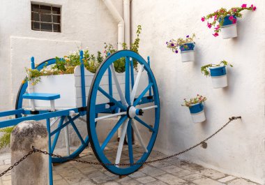 Polignano a Mare 'de çiçeklerle bembeyaz ve maviye boyanmış ahşap bir araba. Apulia, İtalya