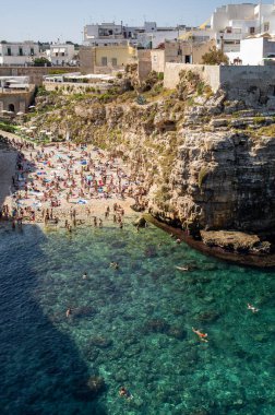 Polignano a Mare, İtalya - 17 Eylül 2019: İnsanlar Polignano a Mare, Adriyatik Denizi, Apulia, Bari ili, İtalya 'daki sevimli Lama Monachile plajında dinleniyor ve yüzüyorlar,