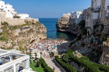 Polignano, İtalya - 17 Eylül 2019: İnsanlar Polignano a Mare, Adriyatik Denizi, Apulia, Bari ili, İtalya 'daki sevimli Lama Monachile plajında dinleniyor ve yüzüyorlar,