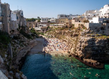 Polignano, İtalya - 17 Eylül 2019: İnsanlar Polignano a Mare, Adriyatik Denizi, Apulia, Bari ili, İtalya 'daki sevimli Lama Monachile plajında dinleniyor ve yüzüyorlar,