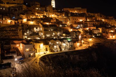 Matera 'daki antik Sassi bölgesinde geceleri, antik mağara evleri ile tanınan şaşırtıcı aydınlık binalar. Basilicata. İtalya