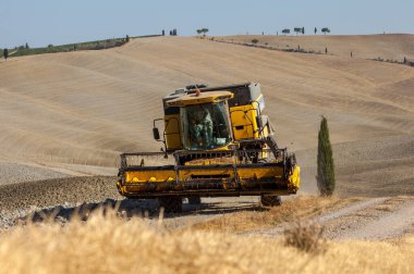 Pienza, İtalya - 13 Eylül 2011: Hasat sırasında hasat makinesini ve Toskana kırsalının manzarasını birleştirin. İtalya