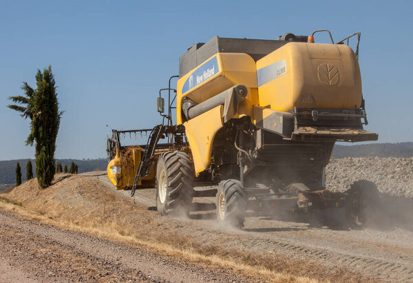 Pienza, Italy - September 13, 2011: Combine harvester during harvest and the rural landscape of the Tuscany. Italy