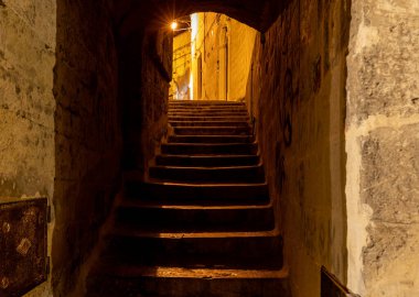 Matera şehrinin tarihi bir bölgesi olan Sassi di Matera 'da bir ara sokaktaki tipik kaldırımlı merdivenler. Basilicata. İtalya