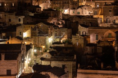 Matera 'daki antik Sassi bölgesinde geceleri, antik mağara evleri ile tanınan şaşırtıcı aydınlık binalar. Basilicata. İtalya