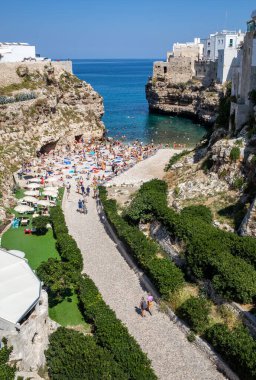 Polignano, İtalya - 17 Eylül 2019: İnsanlar Polignano a Mare, Adriyatik Denizi, Apulia, Bari ili, İtalya 'daki sevimli Lama Monachile plajında dinleniyor ve yüzüyorlar,