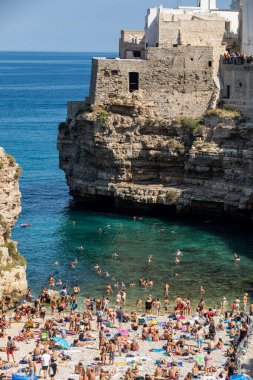 Polignano, İtalya - 17 Eylül 2019: İnsanlar Polignano a Mare, Adriyatik Denizi, Apulia, Bari ili, İtalya 'daki sevimli Lama Monachile plajında dinleniyor ve yüzüyorlar,