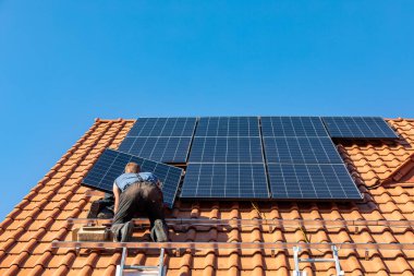  İşçiler Ochojno 'da bir evin çatısına güneş enerjisi panelleri kuruyorlar. Polonya