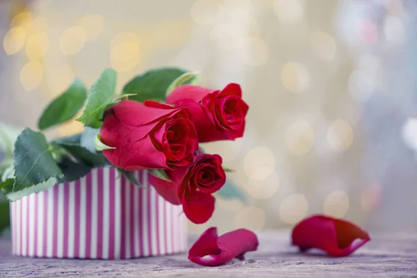 Rote Rosen mit Blütenblättern und Geschenkschachtel für Valentin — Stockfoto