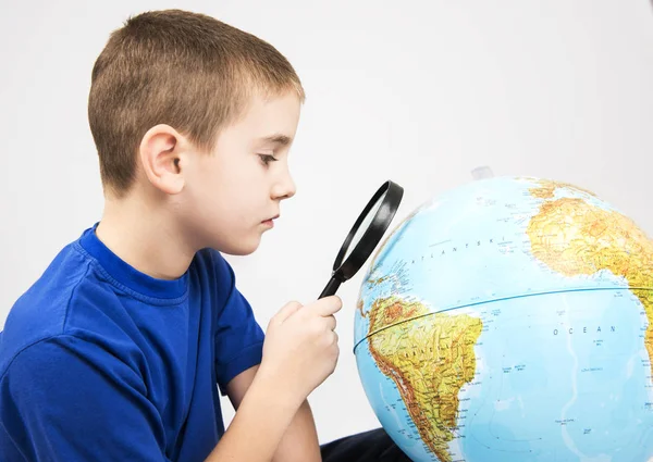 Αγόρι με μεγεθυντικό φακό ψάχνει globe — Φωτογραφία Αρχείου