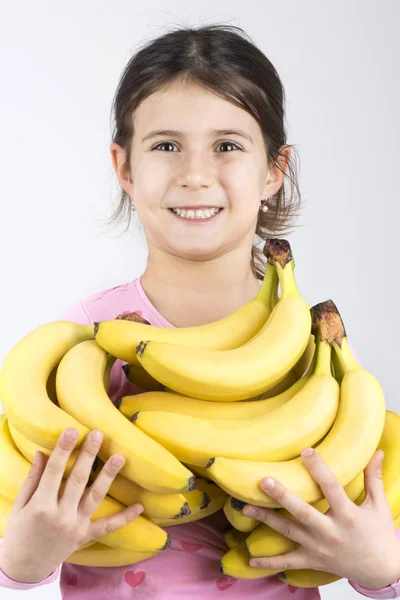 Smiling little girl holding bananas — Stock Photo, Image