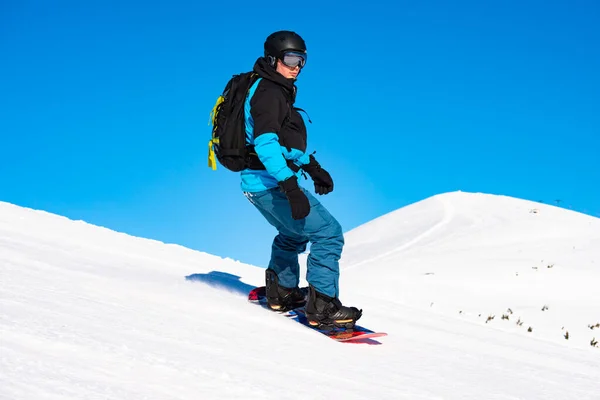 Snowboarder Equitação Snowboard vermelho em montanhas no dia ensolarado. Snowboarding e esportes de inverno — Fotografia de Stock