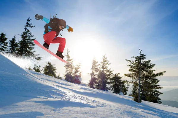 Snowboarder Jumping on the Red Snowboard in Mountains (em inglês) no Sunny Day. Snowboarding e esportes de inverno — Fotografia de Stock