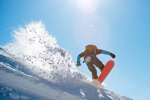 Snowboarder Equitação Snowboard vermelho nas montanhas no dia ensolarado. Grande Mancha de Neve. Snowboarding e esportes de inverno — Fotografia de Stock