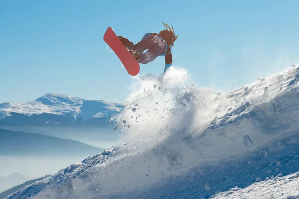 Snowboarder Jumping on Red Snowboard in Mountains (em inglês) no Sunny Day. Snowboarding e esportes de inverno — Fotografia de Stock