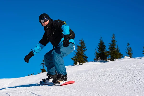 Snowboarder Riding Red Snowboard in Mountains op zonnige dag. Snowboarden en Wintersport — Stockfoto