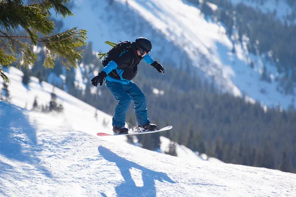 Snowboarder Jumping on the Red Snowboard in Mountains (em inglês) no Sunny Day. Snowboarding e esportes de inverno — Fotografia de Stock