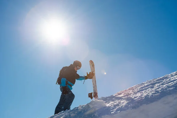 Snowboarder Klimmen met Red Snowboard in de bergen op zonnige dag. Snowboarden en Wintersport — Stockfoto