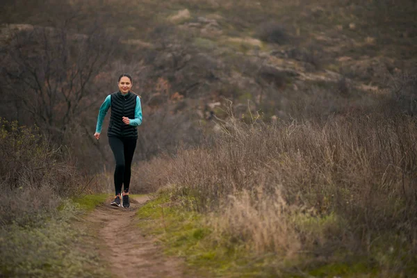 Soğuk sonbahar akşamında dağda koşan güzel gülümseyen kadın. Spor ve Aktif Yaşam Tarzı. — Stok fotoğraf