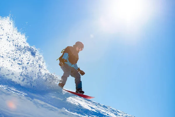 Snowboarder Equitação Snowboard vermelho na encosta nas montanhas em sol brilhante. Snowboarding e conceito de esportes de inverno — Fotografia de Stock