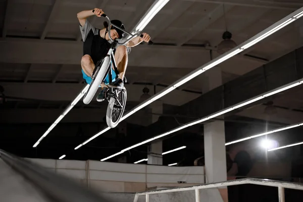 Young BMX Rider Doing Extreme Tricks on the Bike in the Skatepark Indoor. Healthy and Active Lifestyle.