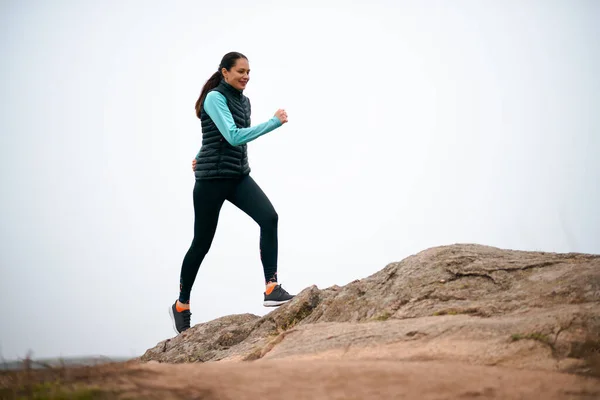 Hermosa mujer sonriente corriendo en el sendero de la montaña en la fría noche de otoño. Deporte y estilo de vida activo . —  Fotos de Stock